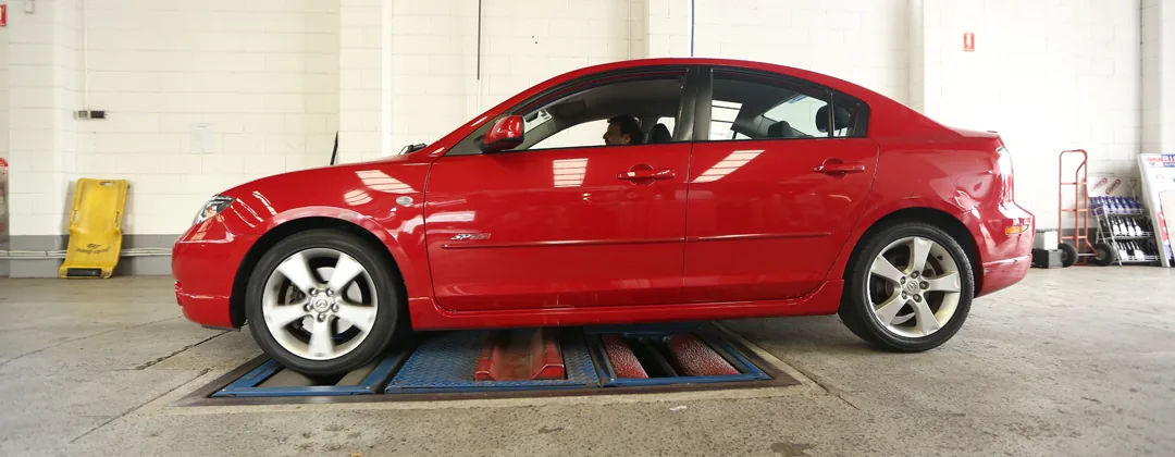 A finished red car in the Pro Paint 'n Panel workshop, ready to be collected.