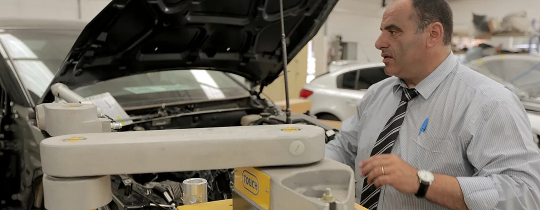 The same BMW X5 on the chassis alignment bench inside the workshop, bonnet up, being measured.